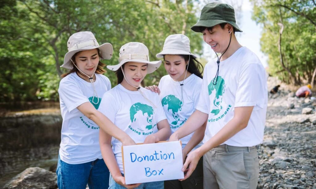 Volunteers in matching t-shirts holding a handmade donation box