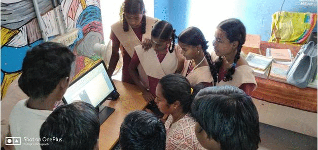Students gathered around a laptop during a Kalvi Kattanam Foundation learning session