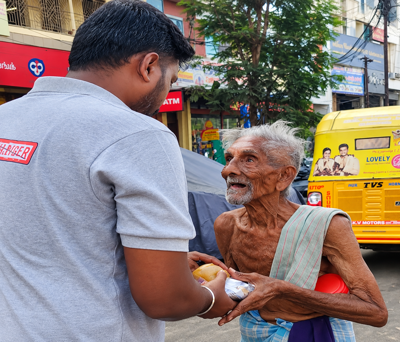 Volunteer handing a freshly packed meal to an elderly man during a Strike The Hunger food round
